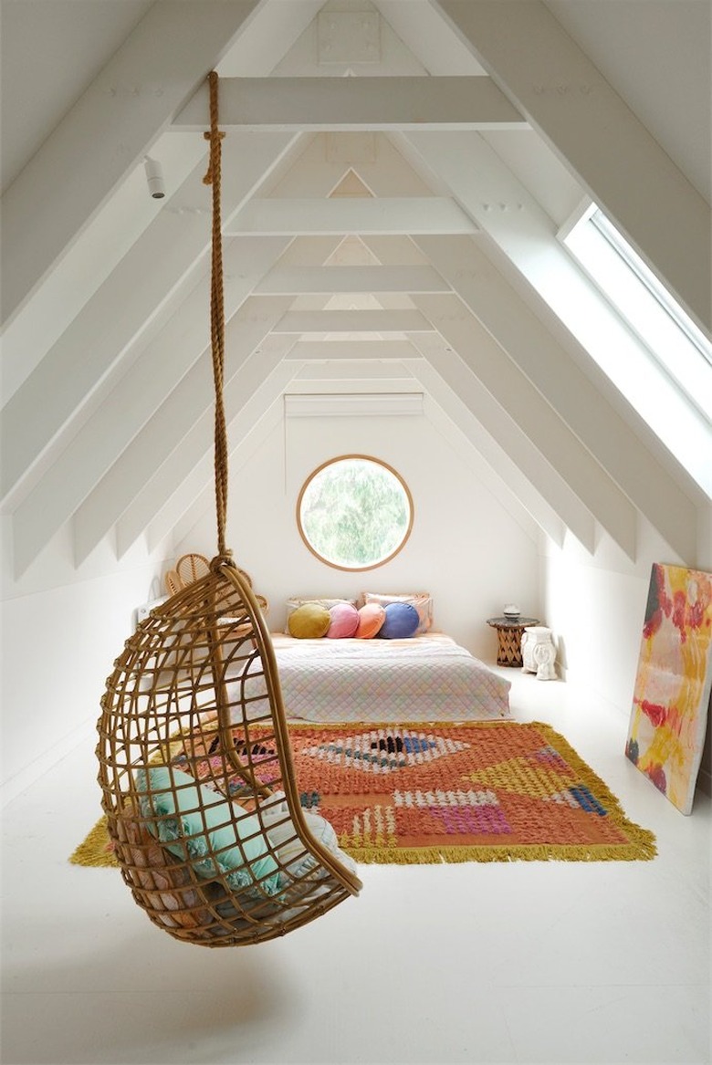 Attic bedroom idea with colorful area rug and rattan hanging chair