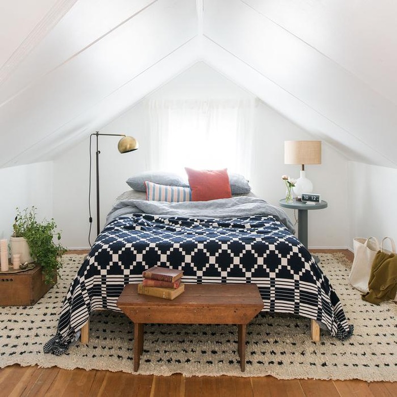 Attic bedroom idea with white walls and bed with navy and white comforter