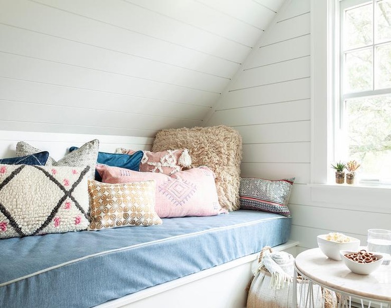 built-in bench in attic playroom with white shiplap and patterned throw pillows