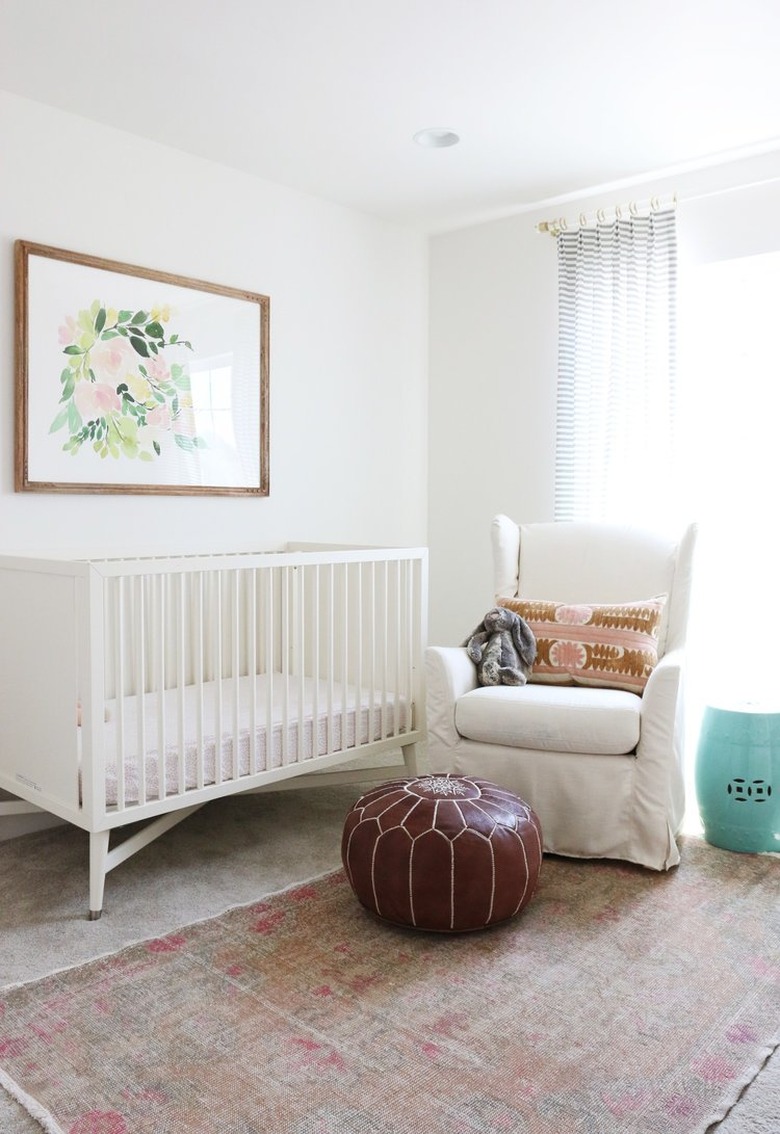 white, pink, and brown nursery idea with upholstered rocking chair and artwork above crib