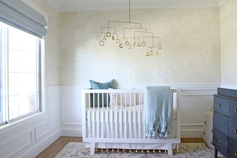 tan and blue nursery idea with mobile hanging above crib and wallpaper on walls