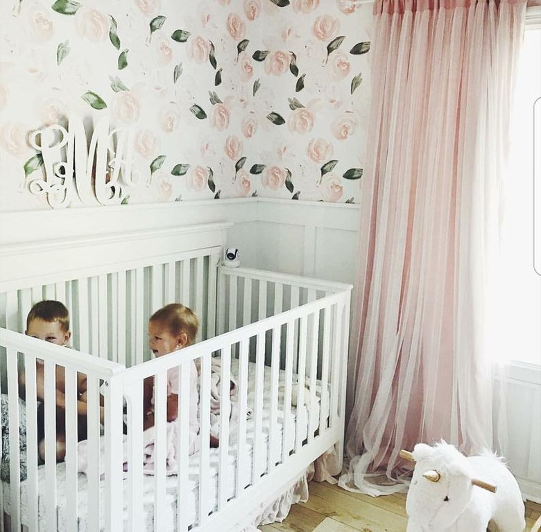 pink and white nursery idea with floral wallpaper and pink drapery