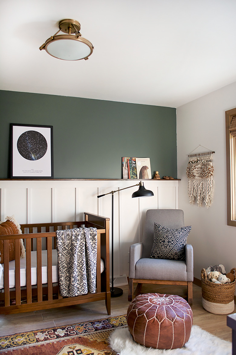 dark green, brown, and white nursery idea with wood crib and rocker in corner with floor lamp