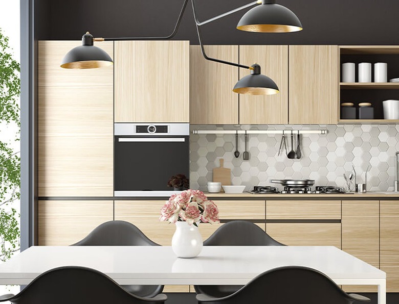 Kitchen with bamboo cabinets, stove, modern lamp, table and chairs.