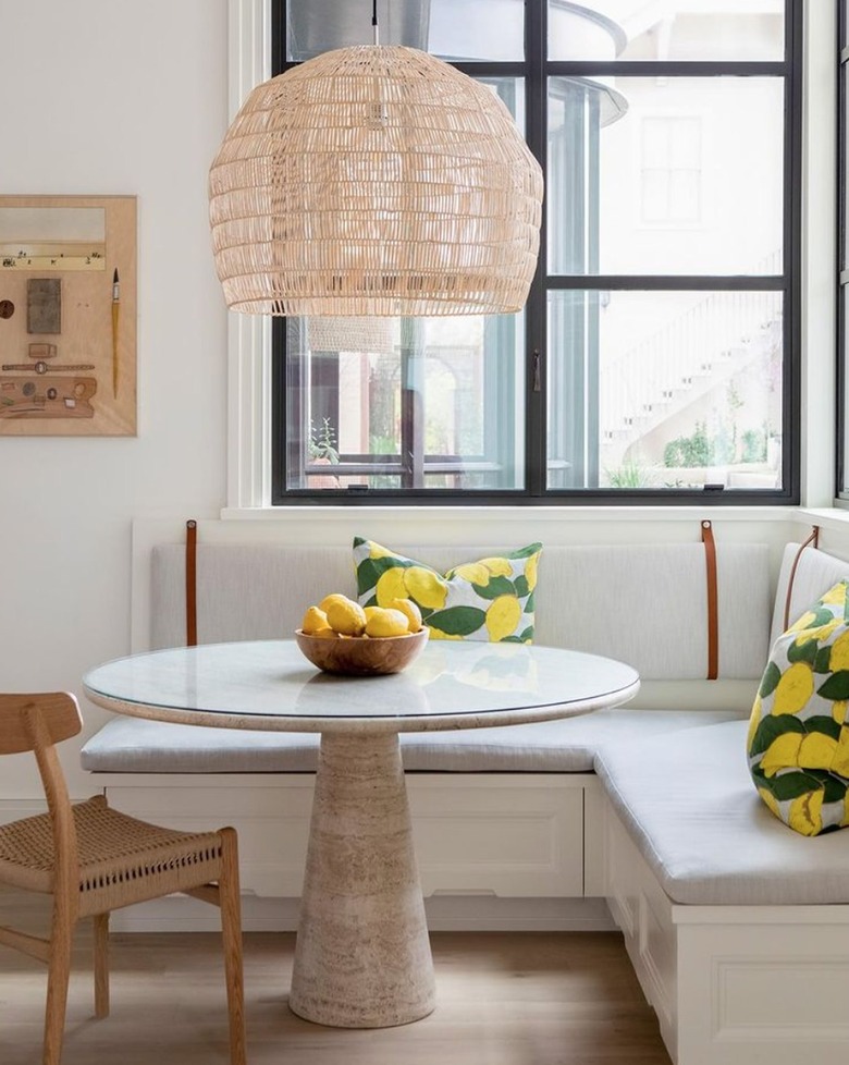 Modern kitchen with banquette dining area, round table, cane pendant.