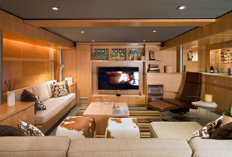 pine basement family room ideas with built-in entertainment system, cream couches, and recessed lighting