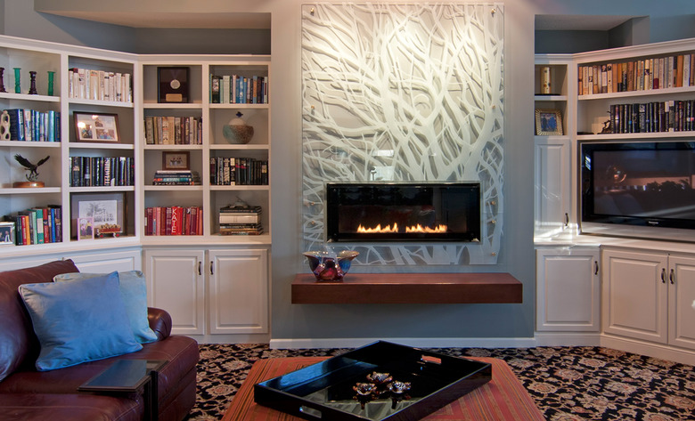 basement fireplace with plexiglass mantel, built-in shelves, and leather couch