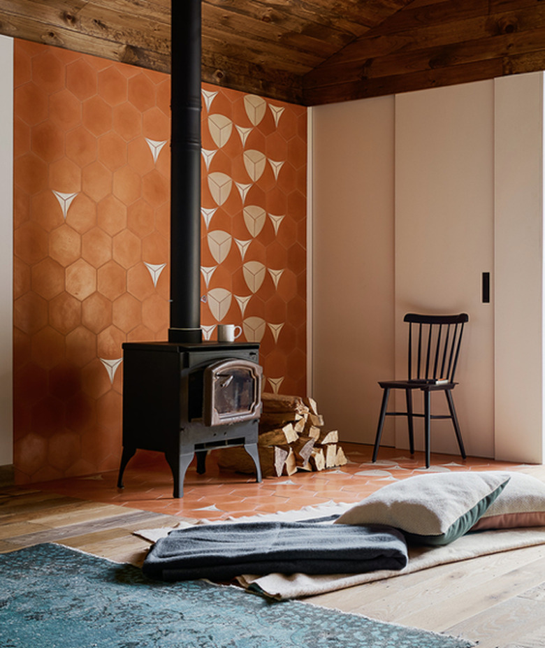 wood-burning basement fireplace in front of floor pillow and orange accent wall