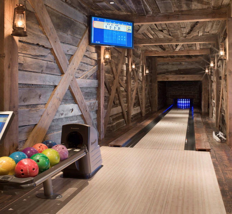 basement game room ideas with rustic wood paneled bowling lane, bowling balls, and flat screen TV