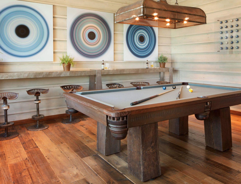 basement game room ideas with rustic pool table, wide plank wood floors, pool ball art, and bar stools