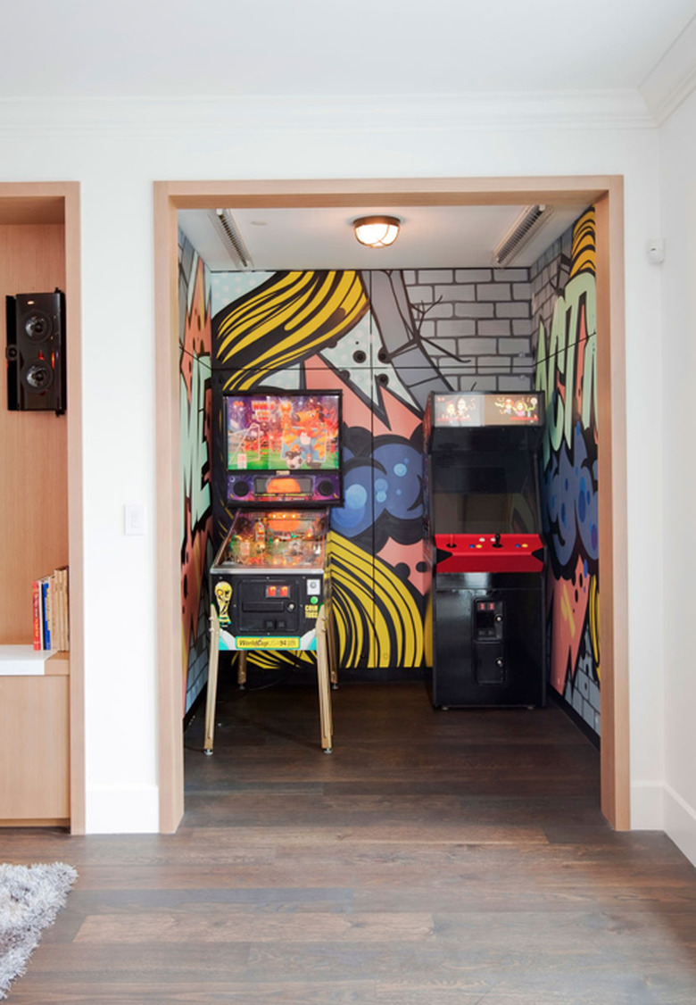 basement game room ideas with street art painted walls in nook with dome light, pinball and arcade game.