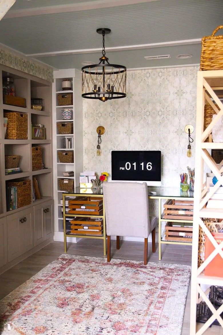 modern basement office with patterned wallpaper accent wall and sconces