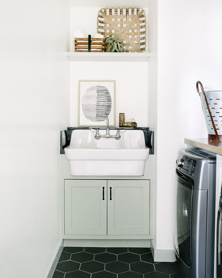 basement laundry room ideas with black hexagon tile floor and white sink.