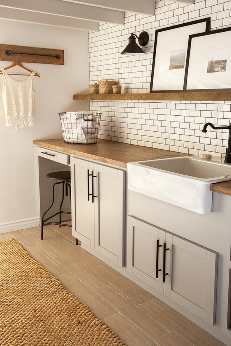 country-chic basement laundry room ideas with white subway tile and gray cabinets