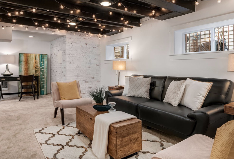 basement lighting in basement with Black leather couch, beige side chairs, wood chest, and criss cross area rug