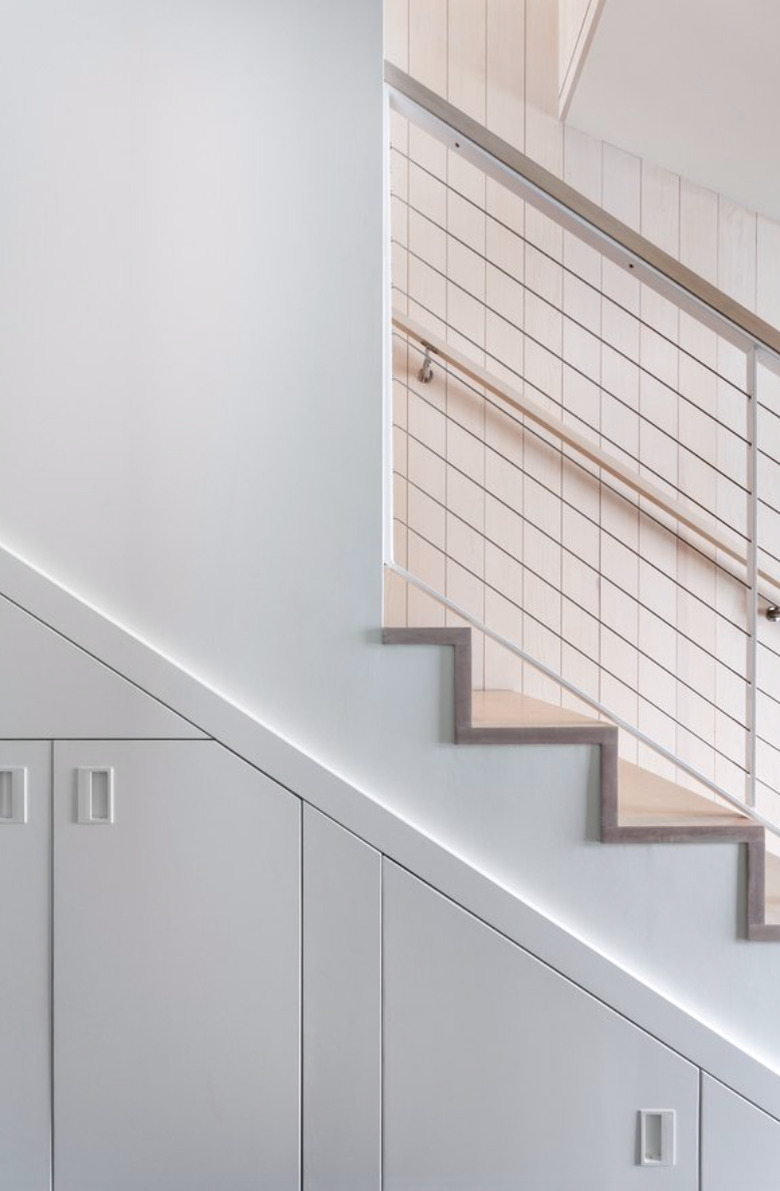 basement storage ideas with white built-in cabinets below stairs