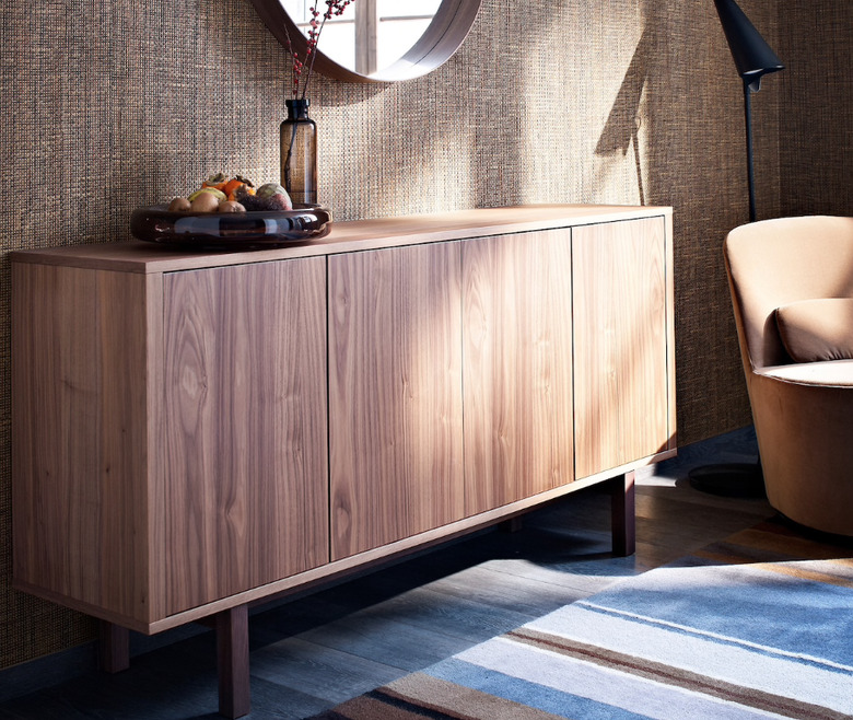 basement storage ideas with natural wood credenza, round mirror, and striped area rug