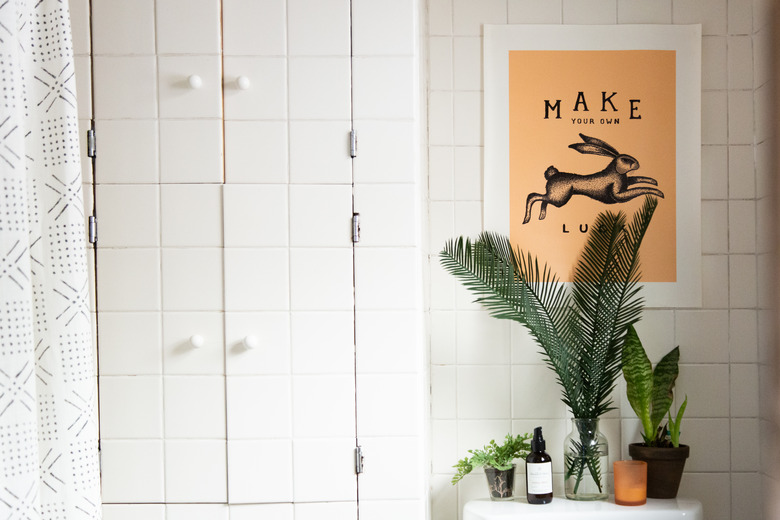 bathroom decor idea with artwork on the wall and greenery with tile walls