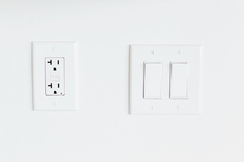 Double light switch and an outlet on a white wall.