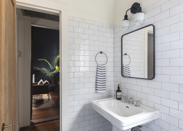 bathroom pedestal sink, subway tile wall tile, mirror and light fixture above