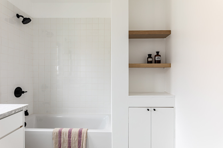 white tile, white combination tub and shower, built-in wood shelves