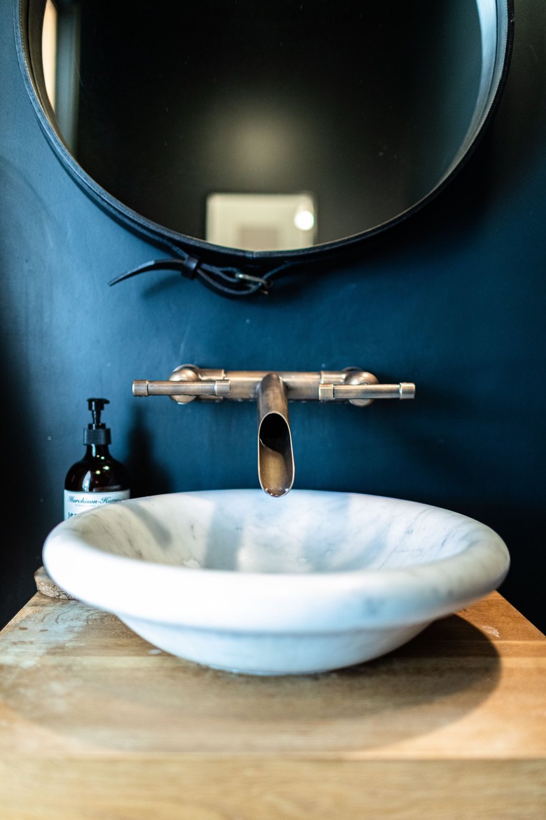 A white sink basin with a contemporary faucet in a bathroom with blue walls