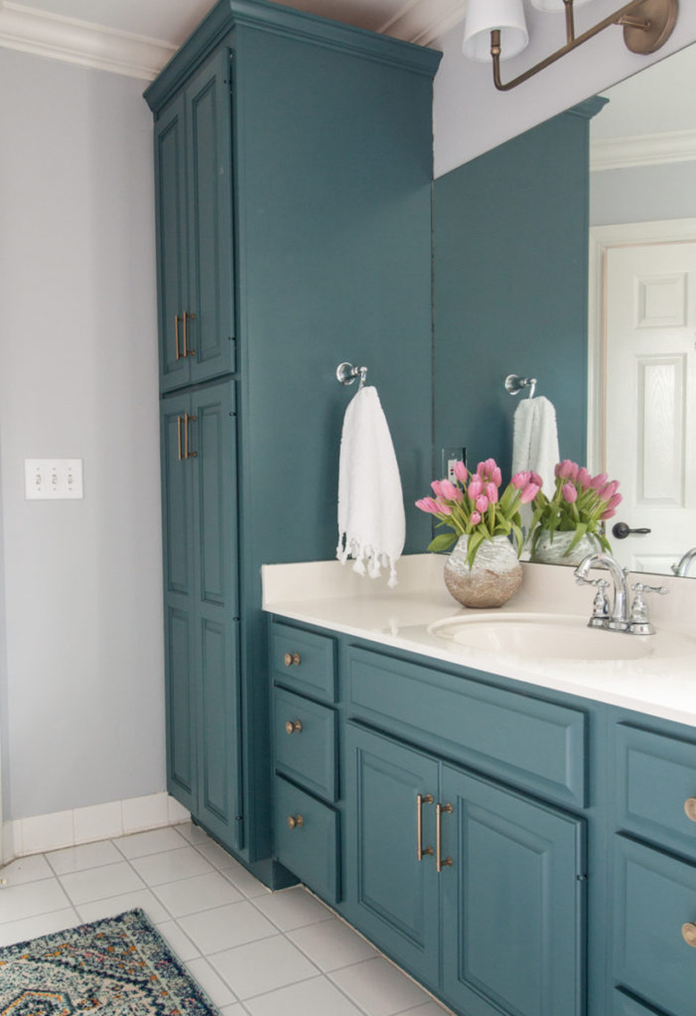 Teal bathroom cabinets with white countertop and white tile floor