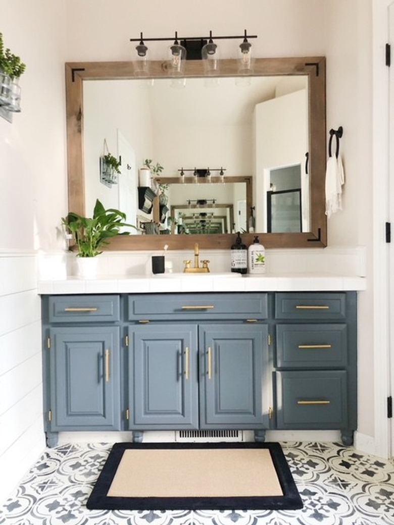 Blue gray cabinets in farmhouse bathroom with cement tile and wood framed mirror