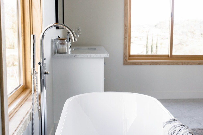 sliding bathroom windows in bathroom with white standing tub and silver faucet