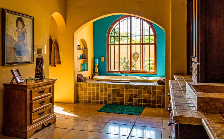 arched bathroom windows with in bathroom with large floor tiles and and drop-in tub