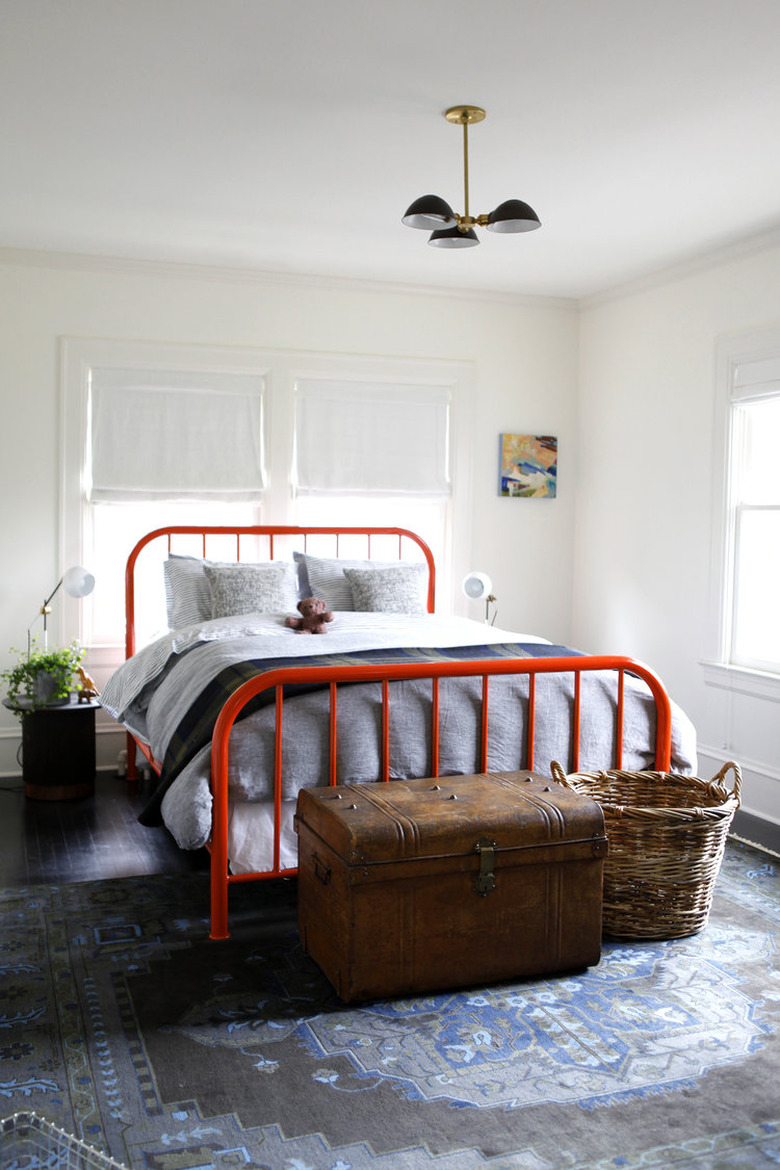 Midcentury-Style bedroom chandelier hanging above red bed frame