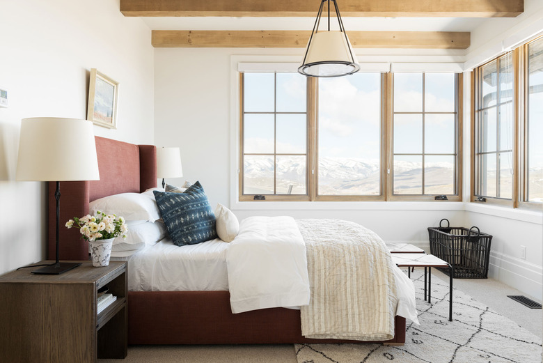 rustic bedroom chandelier hanging above bed with upholstered headboard