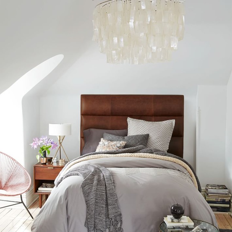 bedroom chandelier hanging above bed with leather upholstered headboard