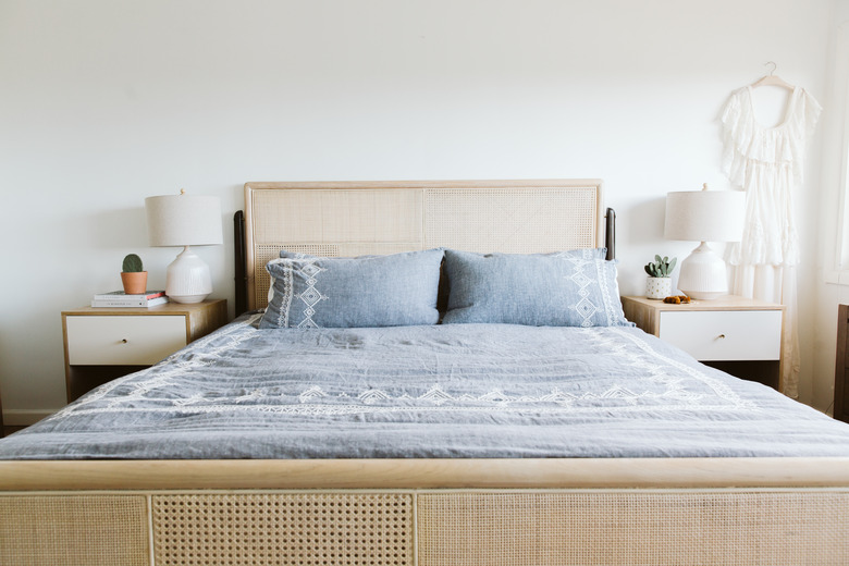 Bed with cane bed frame and headboard, and blue bedspread