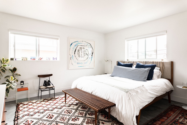 Bedroom with art on the wall and patterned rug.