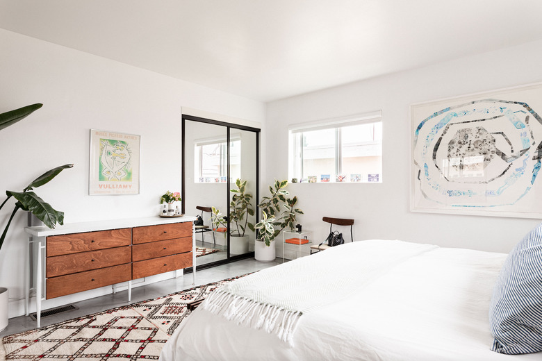 bedroom storage idea with midcentury dresser and mirrored closet doors