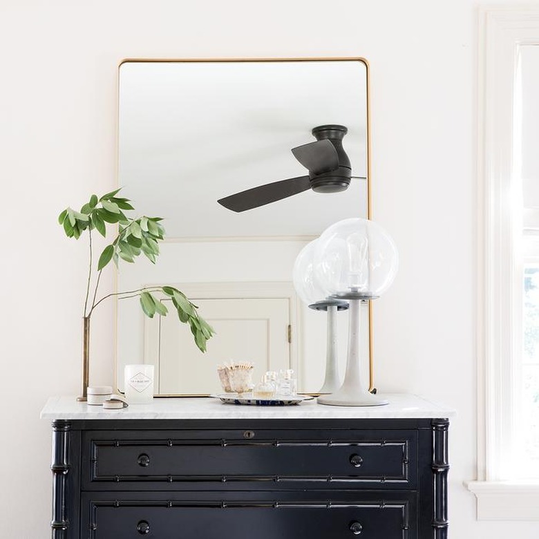 bedroom mirror with brass frame on chest of drawers with marble top