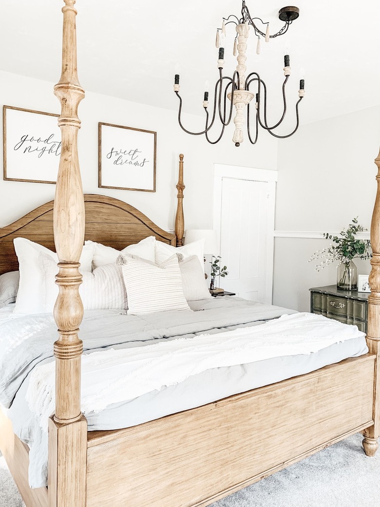 Farmhouse bedroom style with four poster wooden bed and candelabra chandelier