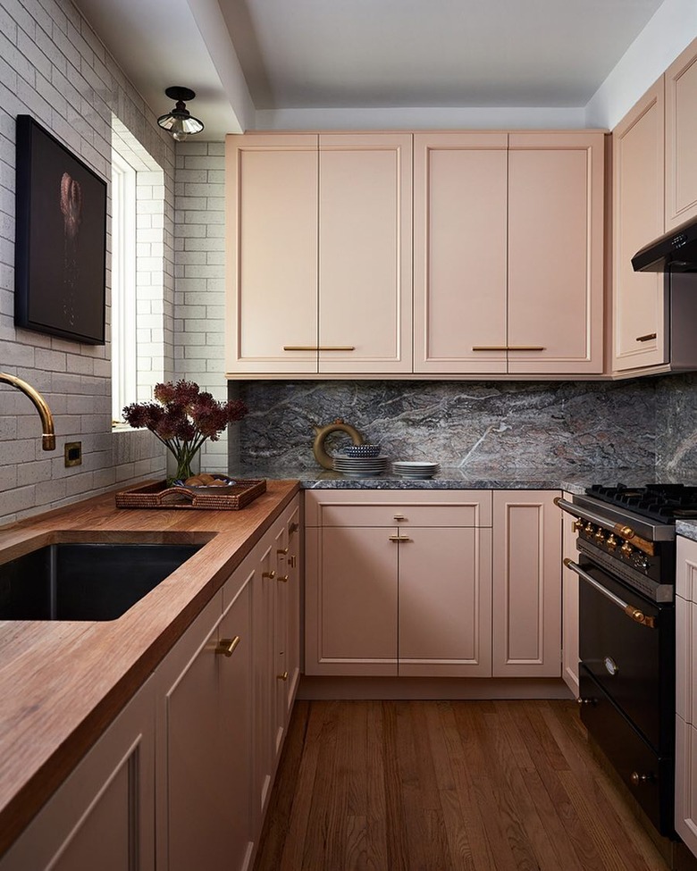 Kitchen with dusky pink cabinets and subway tile on walls with marble backsplash