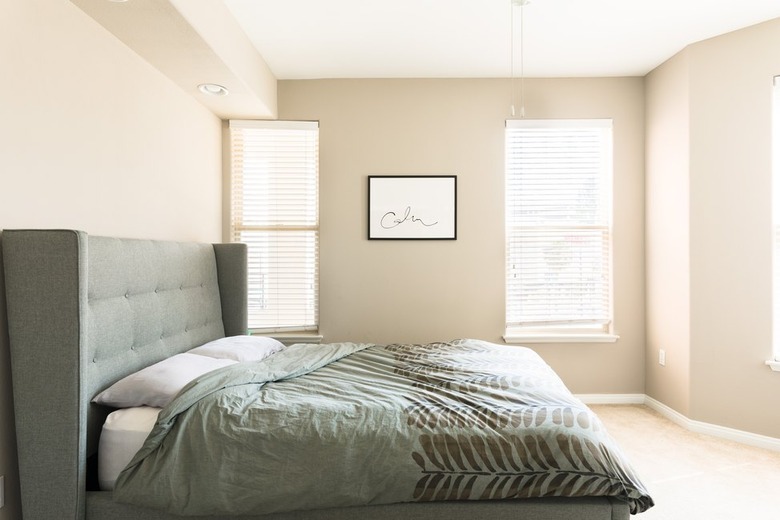 minimalist beige bedroom with green headboard and bedding