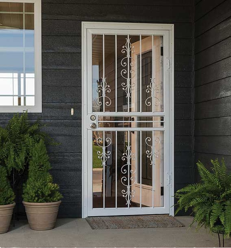 An storm door with iron detail on a house with gray siding