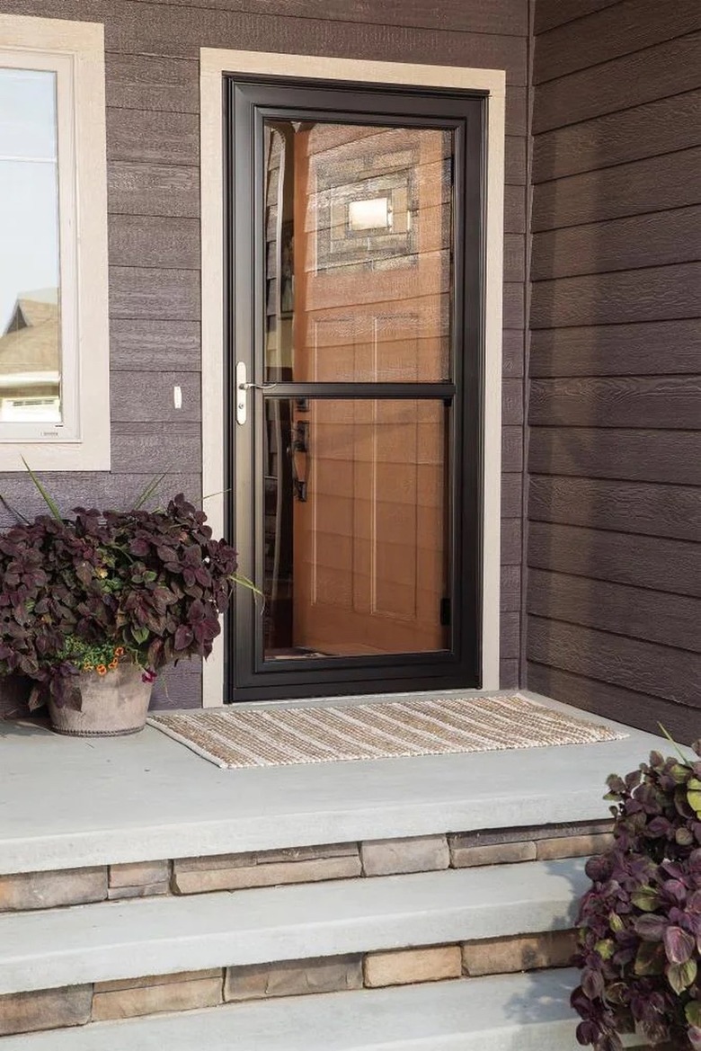 A black storm door on a house with gray siding