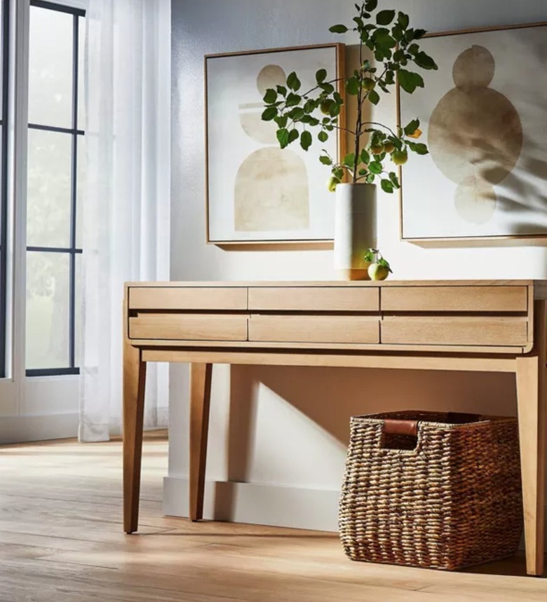 Light-wood console table with drawers, vase, art, basket