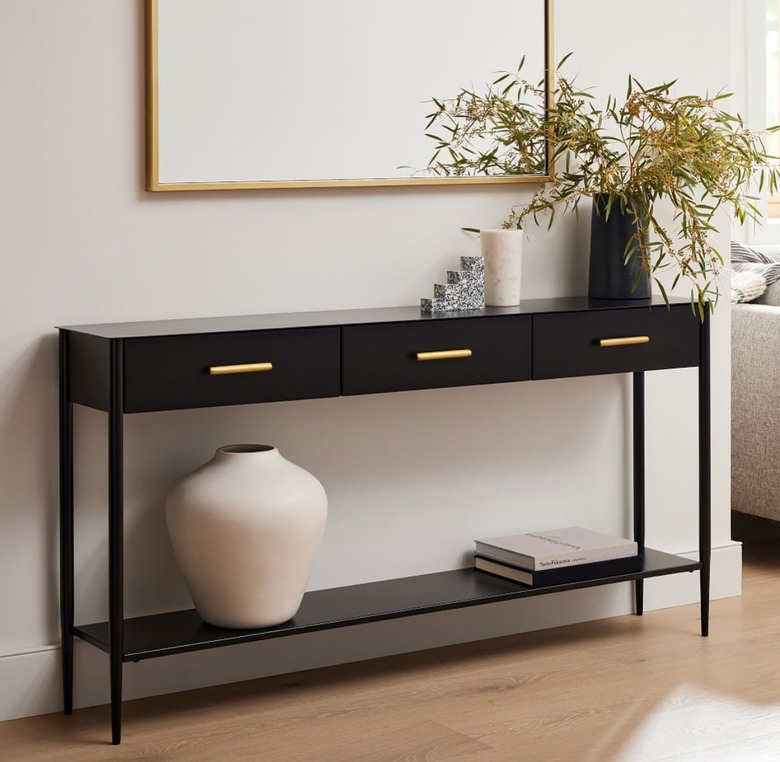 Black console table with drawers, shelf, vases, books, mirror.