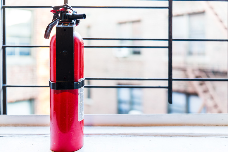 Small apartment red fire extinguisher safety by window in New York City NYC urban Bronx, Brooklyn brick housing, guard rail, security bars