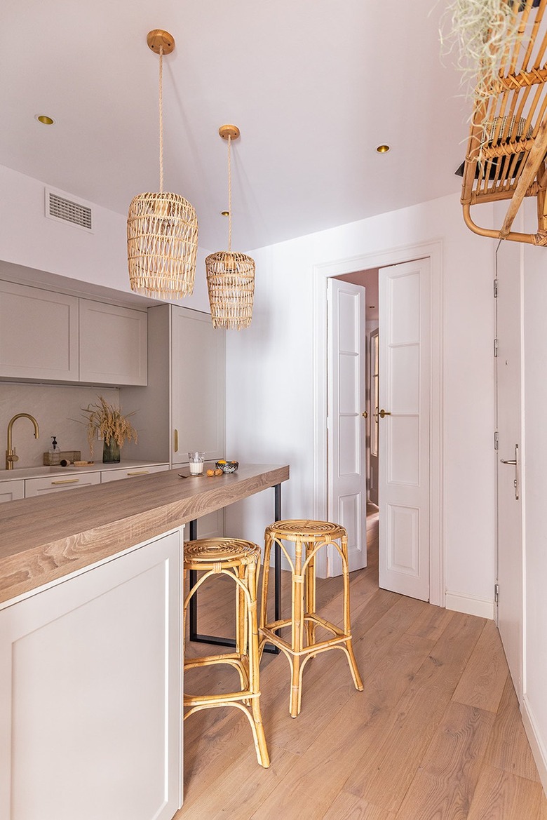 off-white kitchen with rattan pendant lights and wooden stools