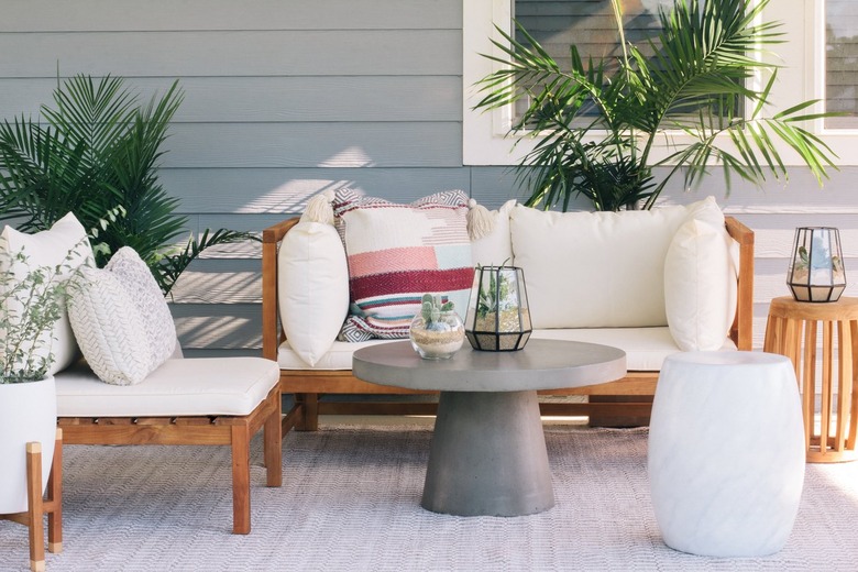 Round gray table with succulent terrariums and white cushioned deck furniture