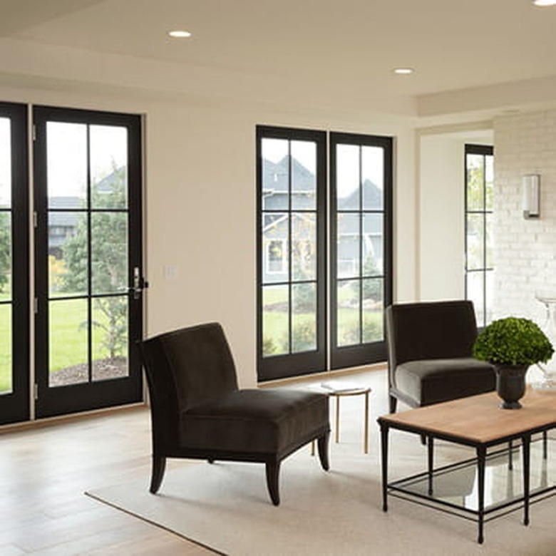 Image of glass patio doors. Room is cream colored with two green chairs and a coffee table