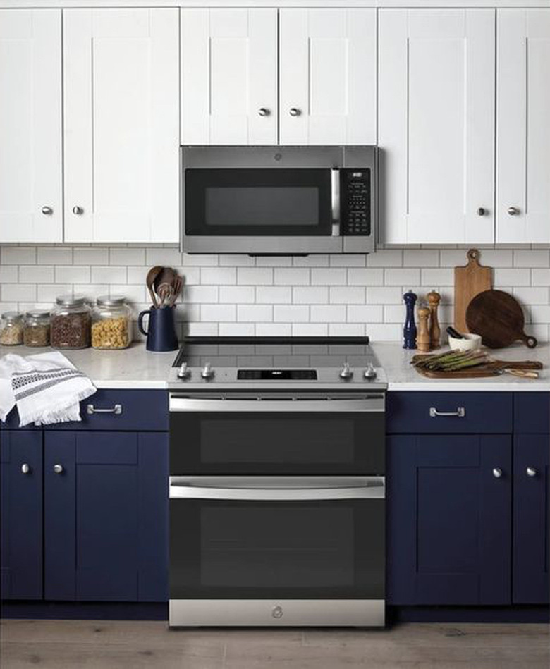 stove brand GE in a blue and white kitchen with stove and microwave