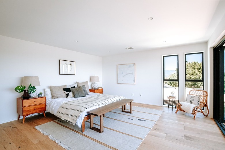 Bedroom with wood furniture, white-beige bedding, wood furniture, and rectangular windows